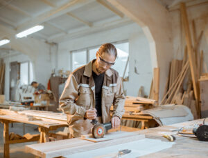 A man wearing safety glasses sanding wood